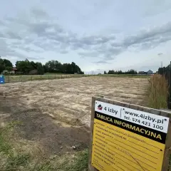 Tablica informacyjna budowy na placu budowy z koparką i toaletą.