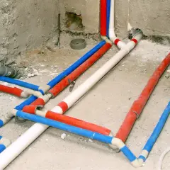 Skomplikowana instalacja wodna w domu, z rurami w kolorach czerwonym, niebieskim i białym, przygotowana do ukrycia pod tynkiem.