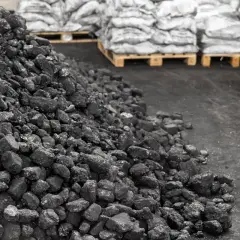 Góra węgla na składzie, obok palety z workami. Aktualna cena węgla na składach budzi niepokój.