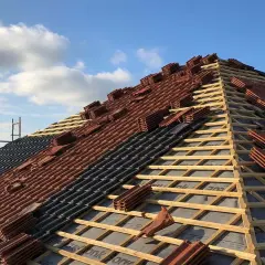 Budowa dachu w toku: łaty i kontrłaty rozstawione, przygotowane pod dachówki. Niebo z chmurami.
