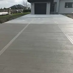Nowy podjazd z beton stemplowany, z wyraźnymi liniami podziału, prowadzi do nowoczesnego domu.