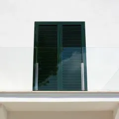 Nowoczesny balkon z przeszkloną balustradą. Okapnik nad oknem zapewnia ochronę przed deszczem.