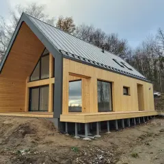 Nowoczesny dom drewniany 70m2 pod klucz, z dużymi oknami i tarasem, otoczony lasem.