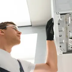 Instalator w okularach ochronnych sprawdza podłączenia kotła, gdzie widoczna jest anoda tytanowa.