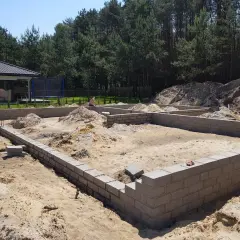 Fundamenty domu w budowie. Piasek, bloczki betonowe i kopce ziemi. To pierwszy krok, od czego zacząć budowę domu.