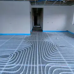 Instalacja ogrzewania podłogowego w nowym domu. Rury ułożone na siatce, gotowe do zalania betonem. To przyszłe oszczędności na koszt ogrzewania podłogowego.