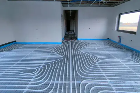 Instalacja ogrzewania podłogowego w nowym domu. Rury ułożone na siatce, gotowe do zalania betonem. To przyszłe oszczędności na koszt ogrzewania podłogowego.