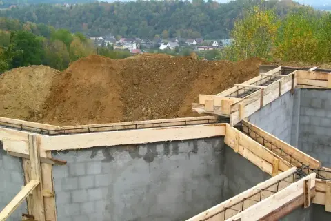Fundamenty domu w budowie, zbrojenie i szalunki czekają na beton. Ważne pozwolenie na budowę to klucz do legalnego stawiania wymarzonego domu.