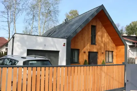 Nowoczesna dobudówka do starego domu, z drewnianą elewacją i garażem. Projekty uwzględniające harmonię z otoczeniem.