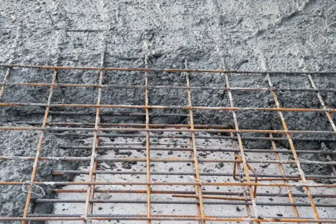 Siatka zbrojeniowa wylewana świeżym betonem, przygotowana do osiągnięcia odpowiednich klas ekspozycji betonu.