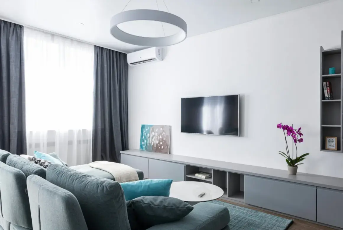 Nowoczesny salon z kanapą, telewizorem i klimatyzacją. Zastanawiasz się, ile kosztuje montaż klimatyzacji?