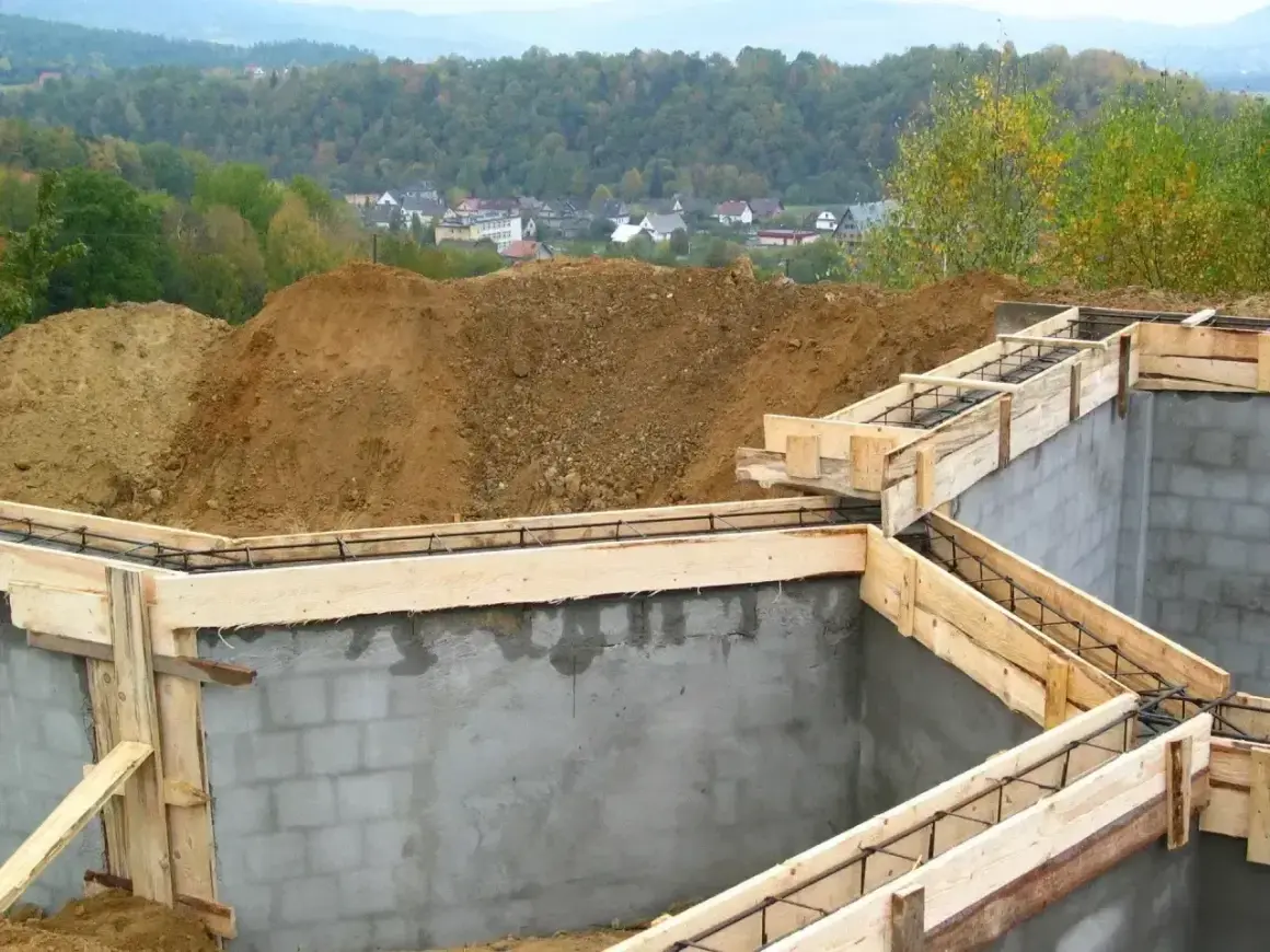 Fundamenty domu w budowie, zbrojenie i szalunki czekają na beton. Ważne pozwolenie na budowę to klucz do legalnego stawiania wymarzonego domu.