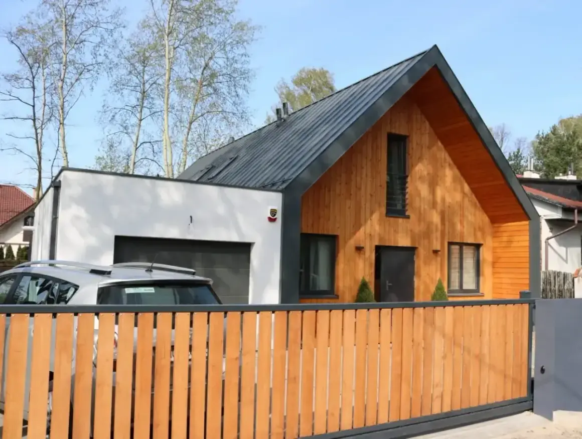 Nowoczesna dobudówka do starego domu, z drewnianą elewacją i garażem. Projekty uwzględniające harmonię z otoczeniem.