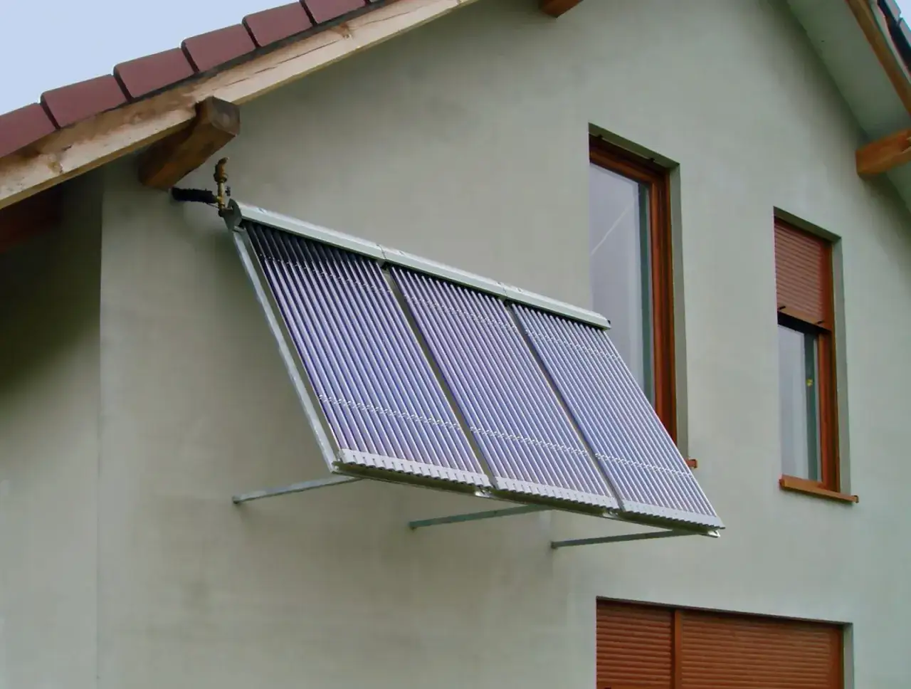 Kolektory solary na ścianie domu, zbierające energię słoneczną do ogrzewania wody.