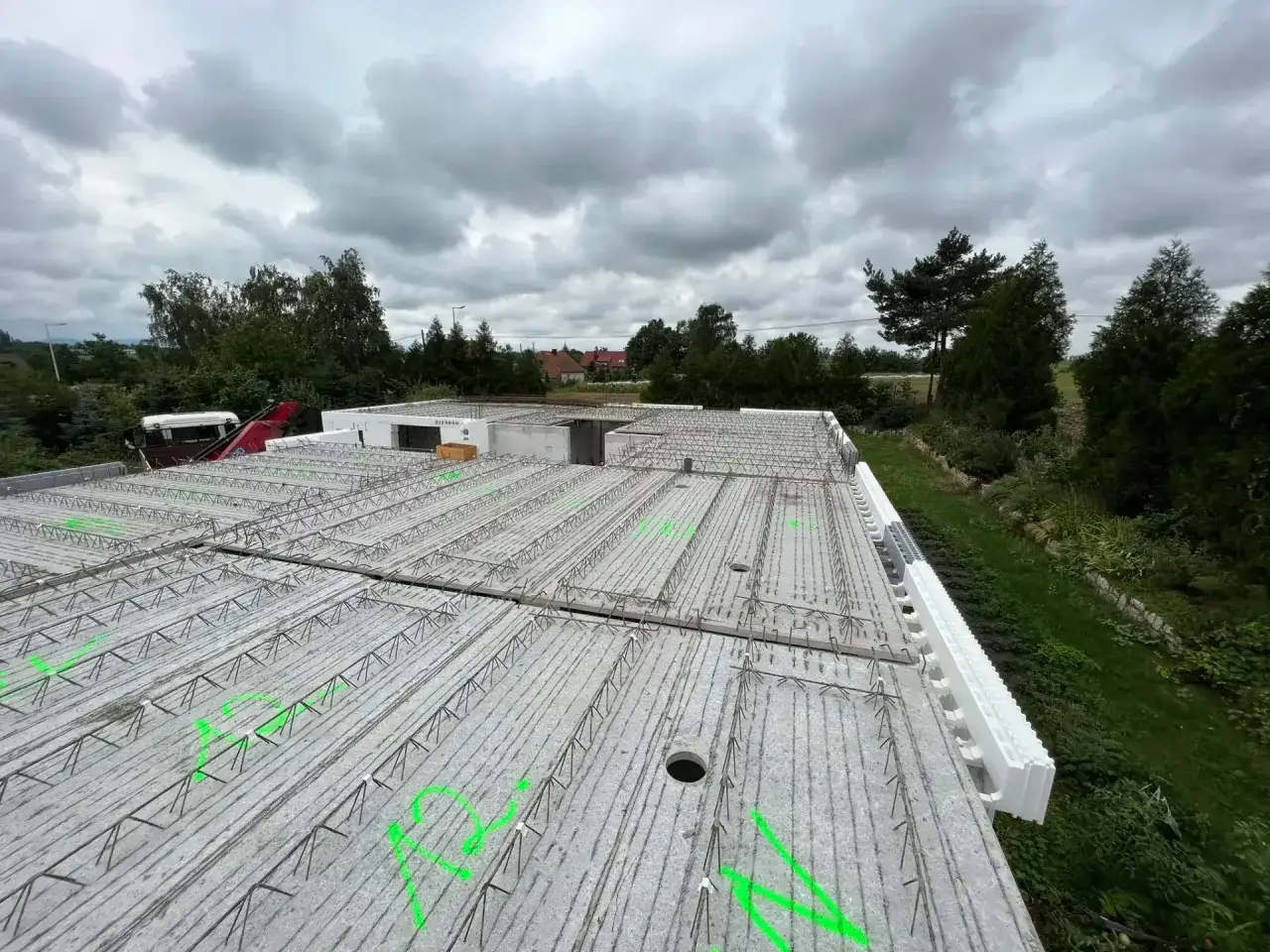 Budowa domu w toku. Widok na strop z prefabrykatów, zbrojenie czeka na beton. Delikatny filigran stalowych prętów tworzy siatkę.