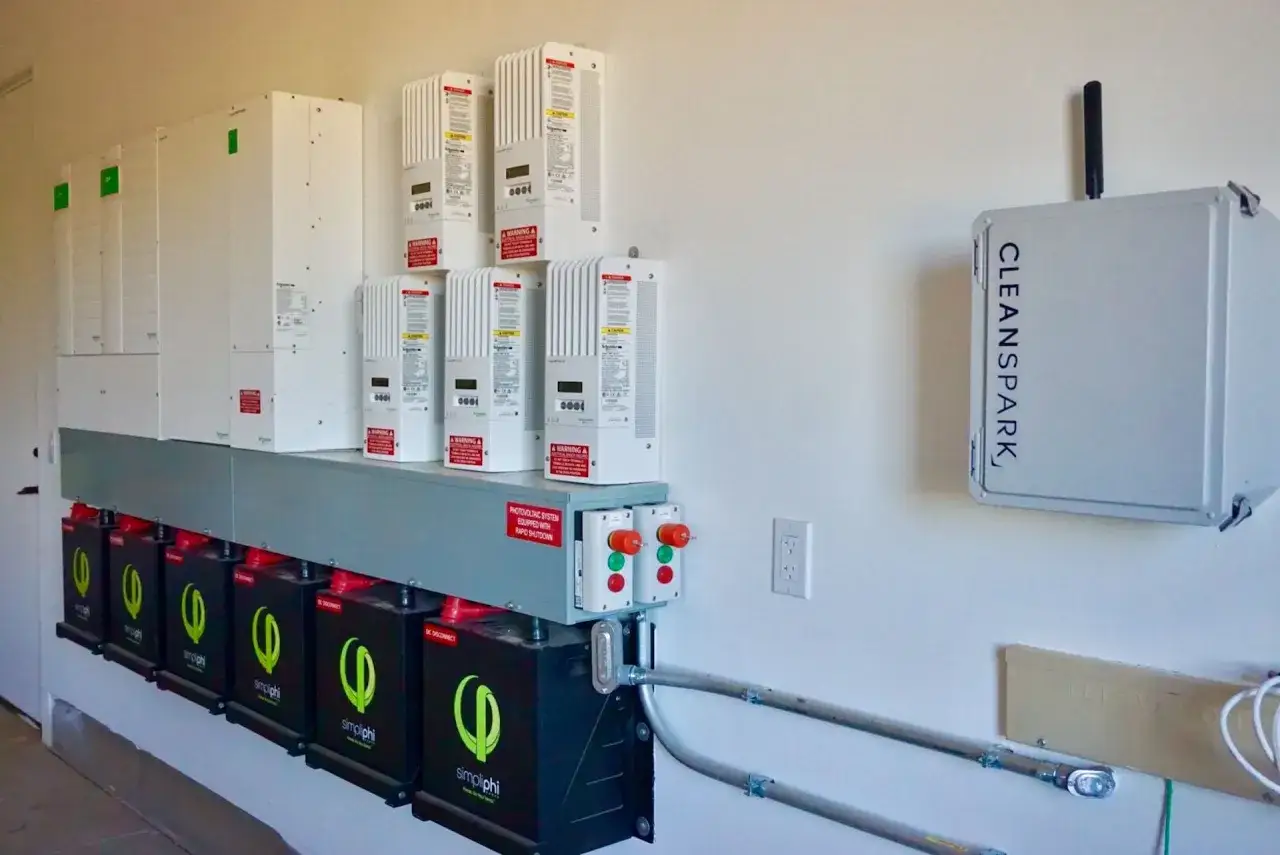 System do magazynowania energii elektrycznej: rzędy baterii i falowników na ścianie, obok urządzenia z napisem