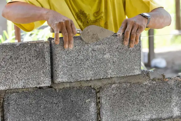 Budowniczy układa bloczki betonowe fundamentowe, tworząc solidną podstawę.
